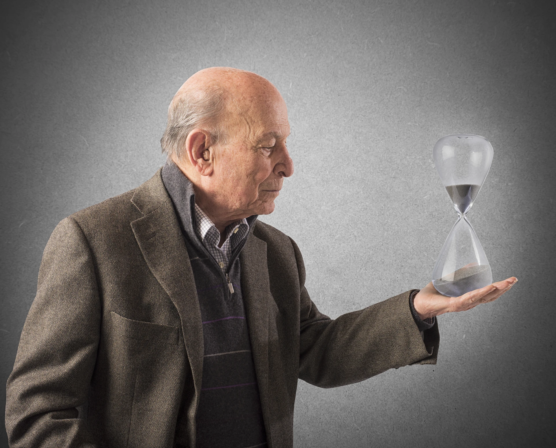 elderly-man-holds-hourglass-hand